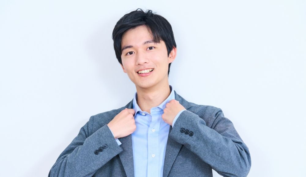笑顔でスーツのジャケットを整える若い男性